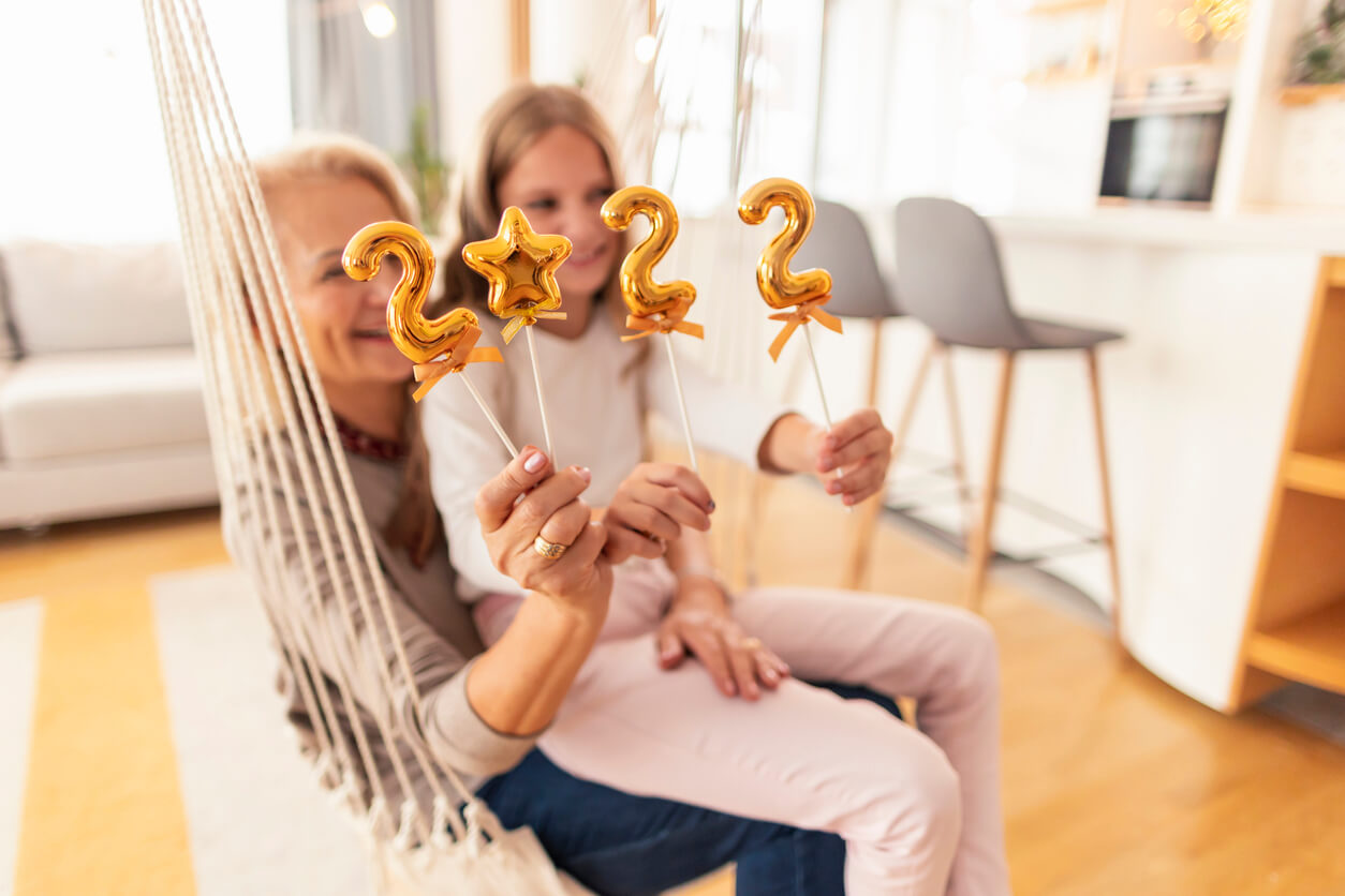 Grandmother and granddaughter holding balloons shaped as numbers 2022