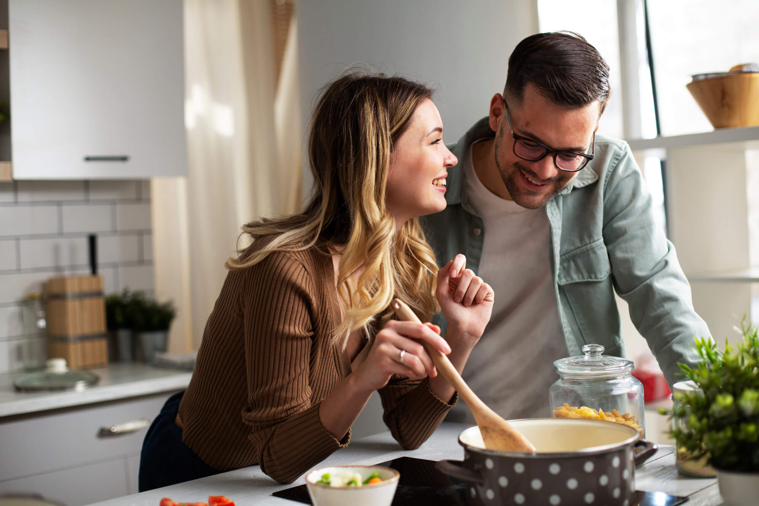 Happy smiling couple cooking together. Boyfriend and girlfriend preparing fresh pasta at home.