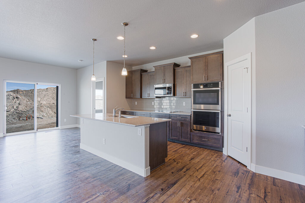 Open kitchen and dining area with island, pendant lights, and sliding glass doors to outside.
