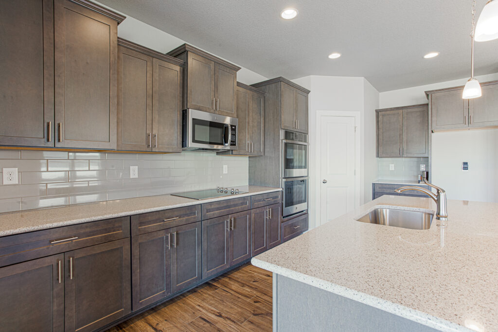 Close view along the kitchen counter showing dark cabinets, cooktop, and island countertop.