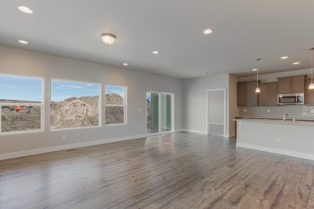 Open-plan living area with large windows, sliding glass door, and kitchen island with pendant lights.