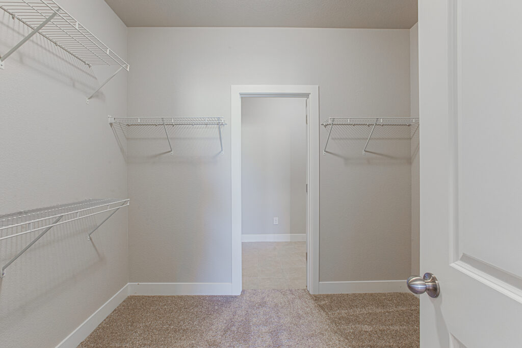 Empty walk-in closet with carpet and wire shelving on three walls.