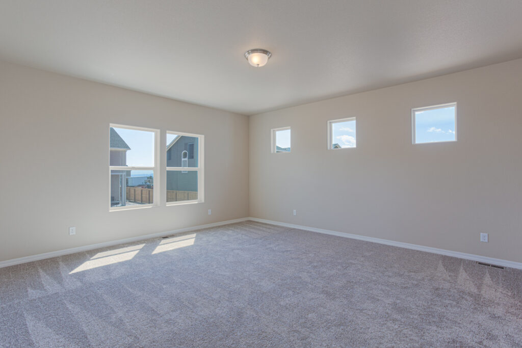 Large airy room with carpet, a wide window, and three small square clerestory windows on the adjacent wall.