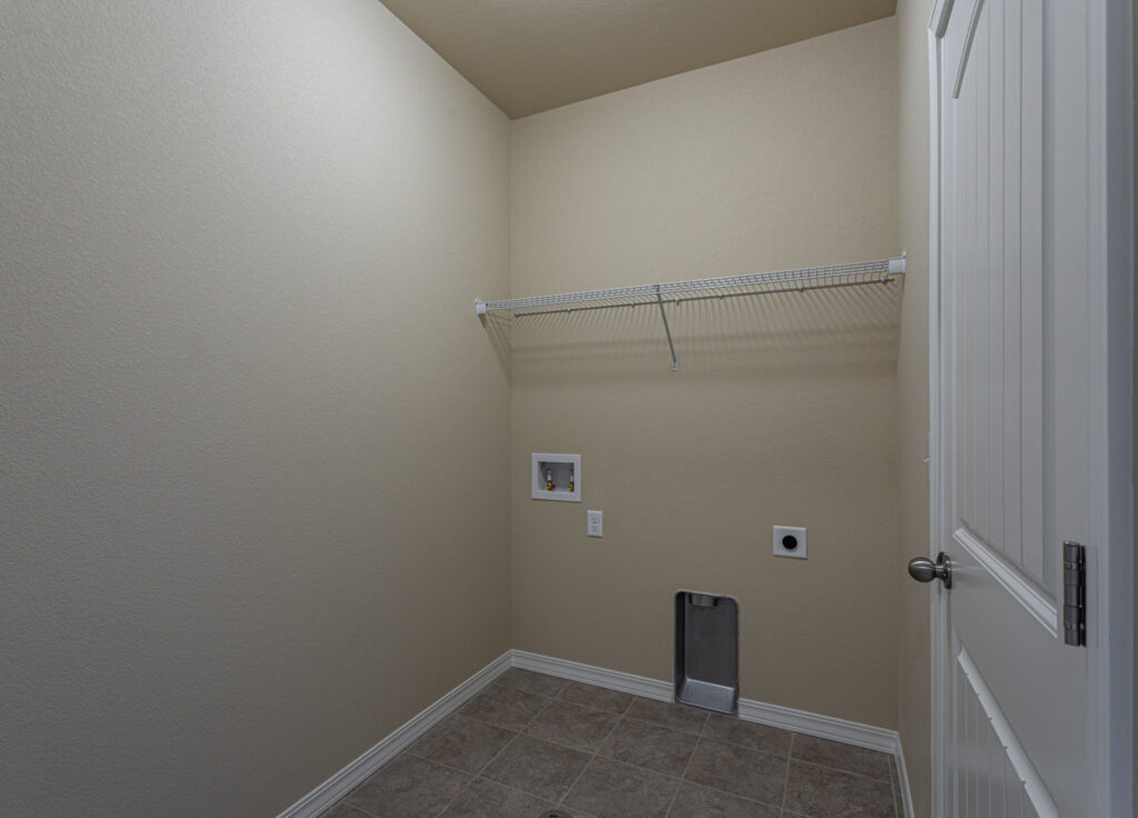 Laundry room with tile floor, single wire shelf, and washer/dryer hookups in the wall.