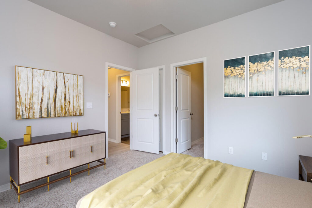 Bedroom perspective showing dresser, wall art, bed corner, and two open interior doors.