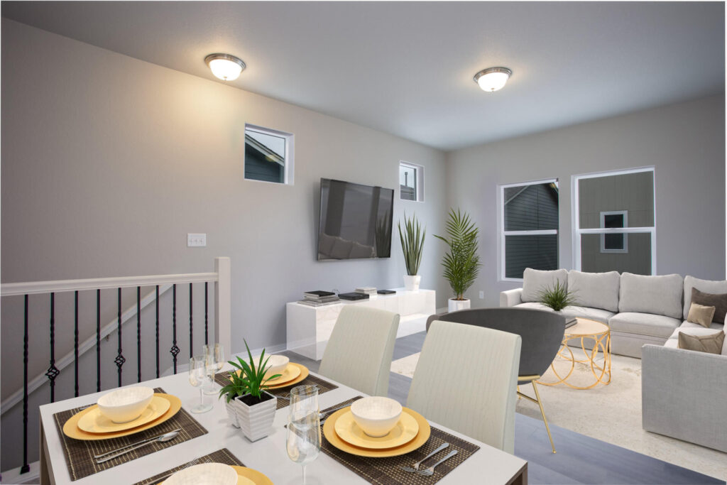 Dining table set for four beside an open living room with wall-mounted TV and small high windows.