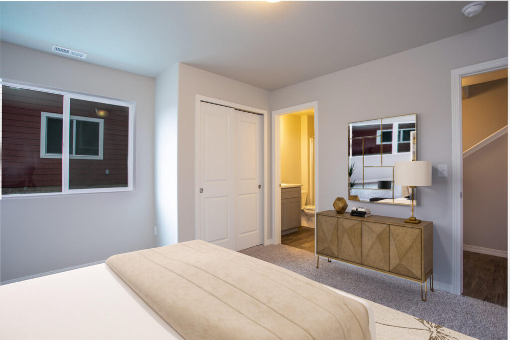 Bedroom view toward closet and dresser, with a bed in foreground and a bathroom doorway open.