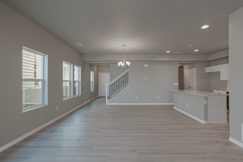 Spacious open living area with multiple windows, dining light fixture, and staircase.