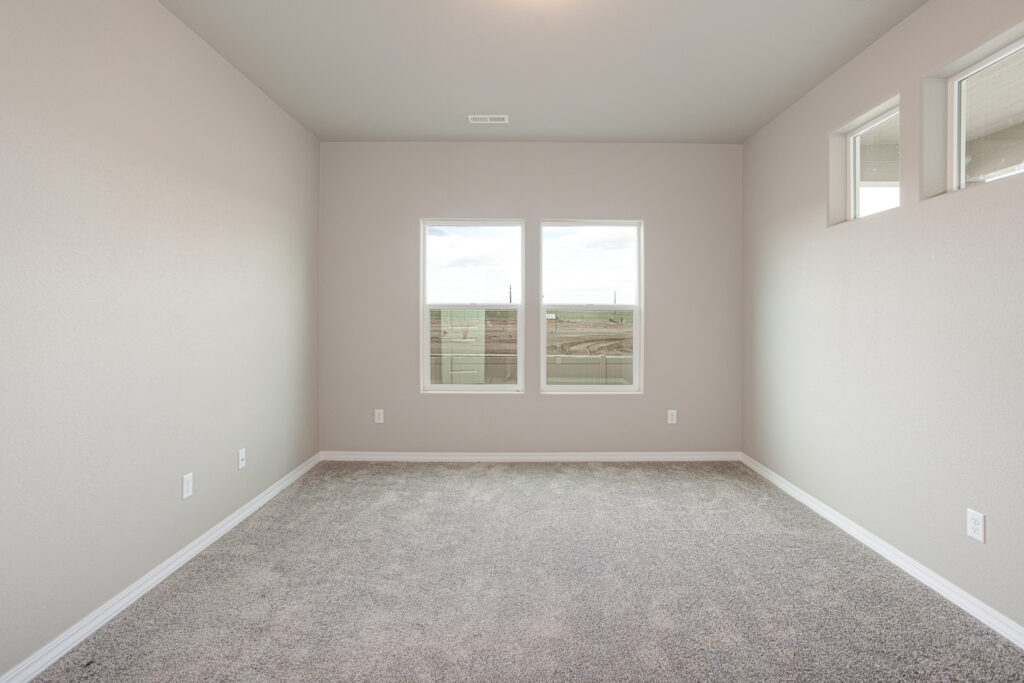 Larger empty room with two main windows and three small clerestory windows.