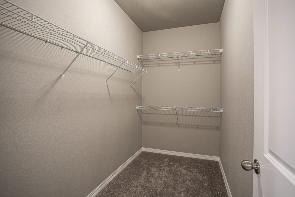 Small walk-in closet with carpeted floor and white wire shelving on three walls.