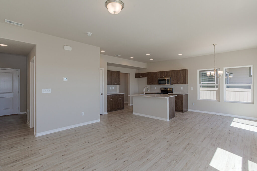 Open-plan living area with kitchen island, light wood floors and neutral walls.