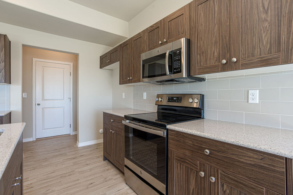 Kitchen countertop and stainless range with over-the-range microwave, wood cabinets and tiled backsplash.