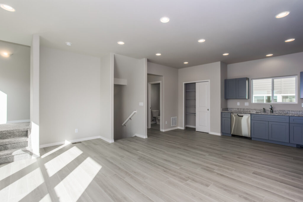 Open living area with wood-look flooring, recessed lights and small kitchenette along one wall.