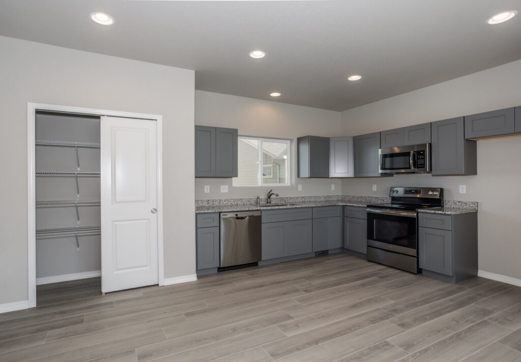 Modern kitchen with gray cabinets, granite-look countertops, pantry and stainless appliances.