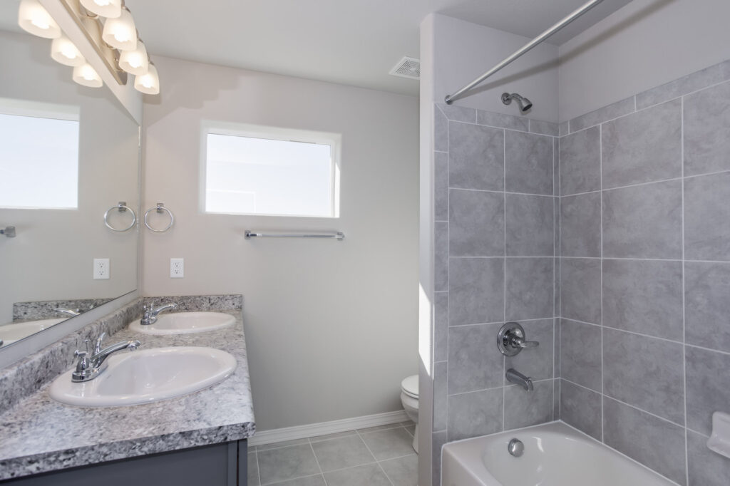 Bathroom with dual sinks on a granite countertop and a tiled tub/shower surround.