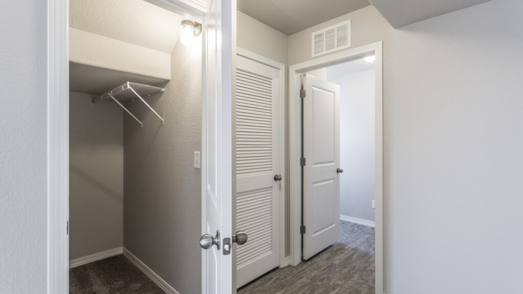 Interior hallway with open closet showing wire shelving and adjacent room doors.