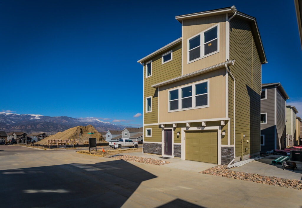 Angled view of the same three-story townhouse with mountain backdrop and neighboring homes.