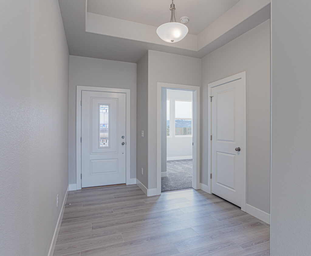 Entryway with front door, interior doors, tray ceiling and wood-look flooring.