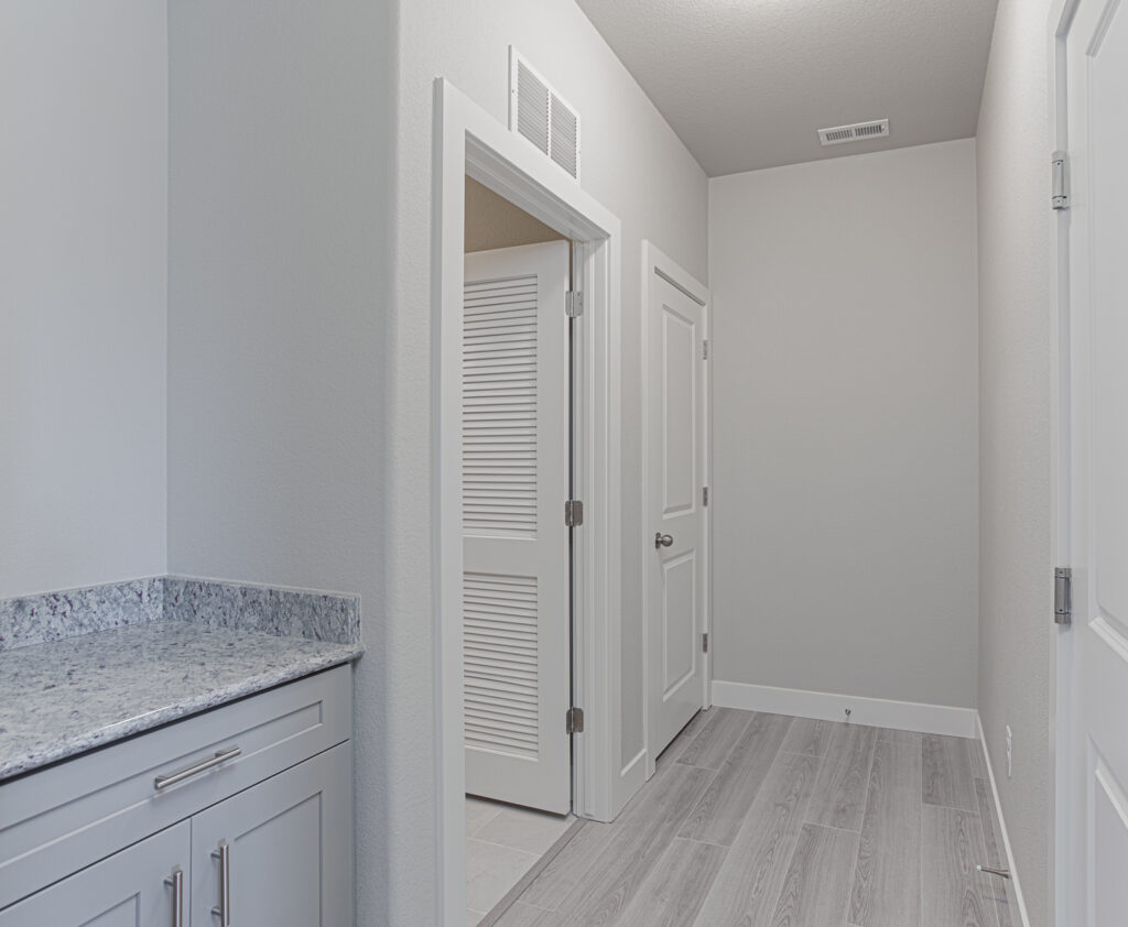 Hallway with built-in cabinet counter, multiple doors and wood-look flooring.