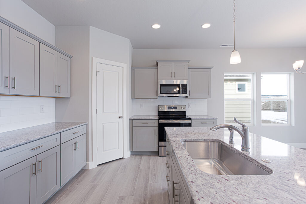 Kitchen countertop close-up with undermount sink, faucet, cabinets, and oven in background.
