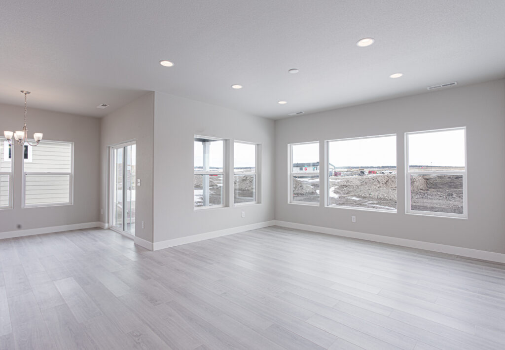 Expansive open living area with multiple windows and sliding door, offering abundant natural light.