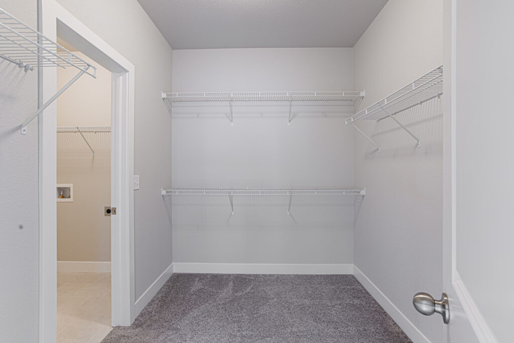 Empty walk-in closet with carpeted floor and multiple wire shelving units.