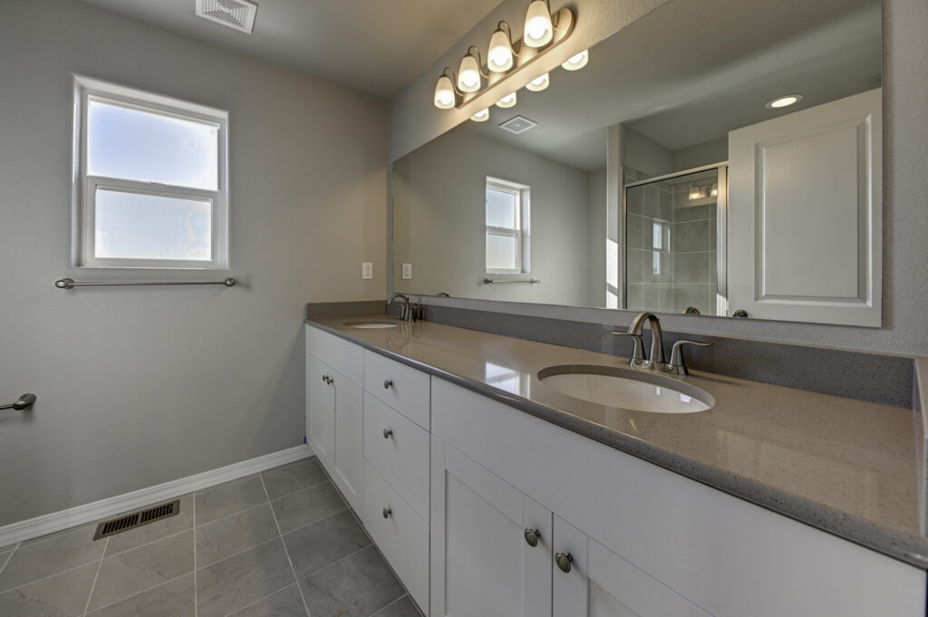 Bathroom vanity with dual sinks, large mirror, and a small frosted window above towel bar.