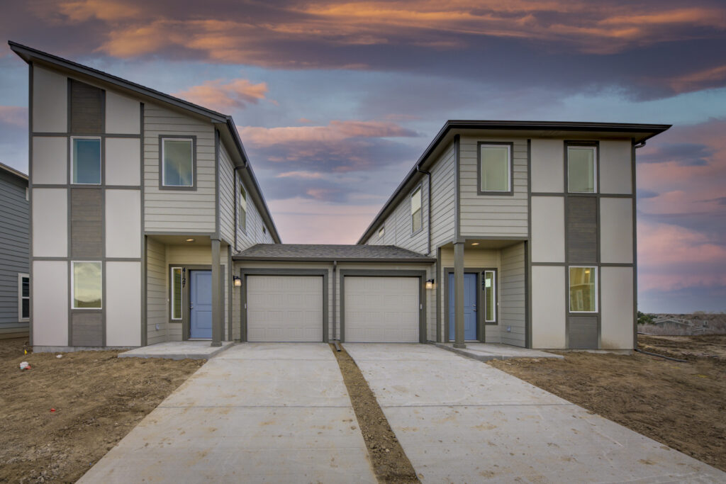 Pair of modern two-story townhomes with attached single-car garages and concrete driveways.