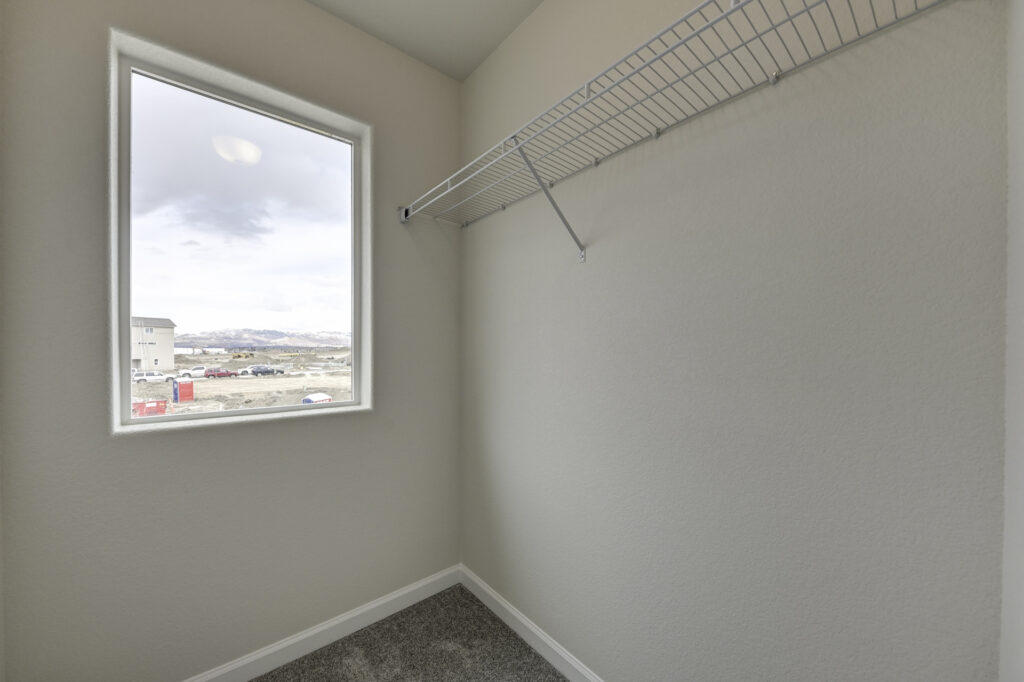 Small closet or storage room with a single window and a wire shelf along one wall.