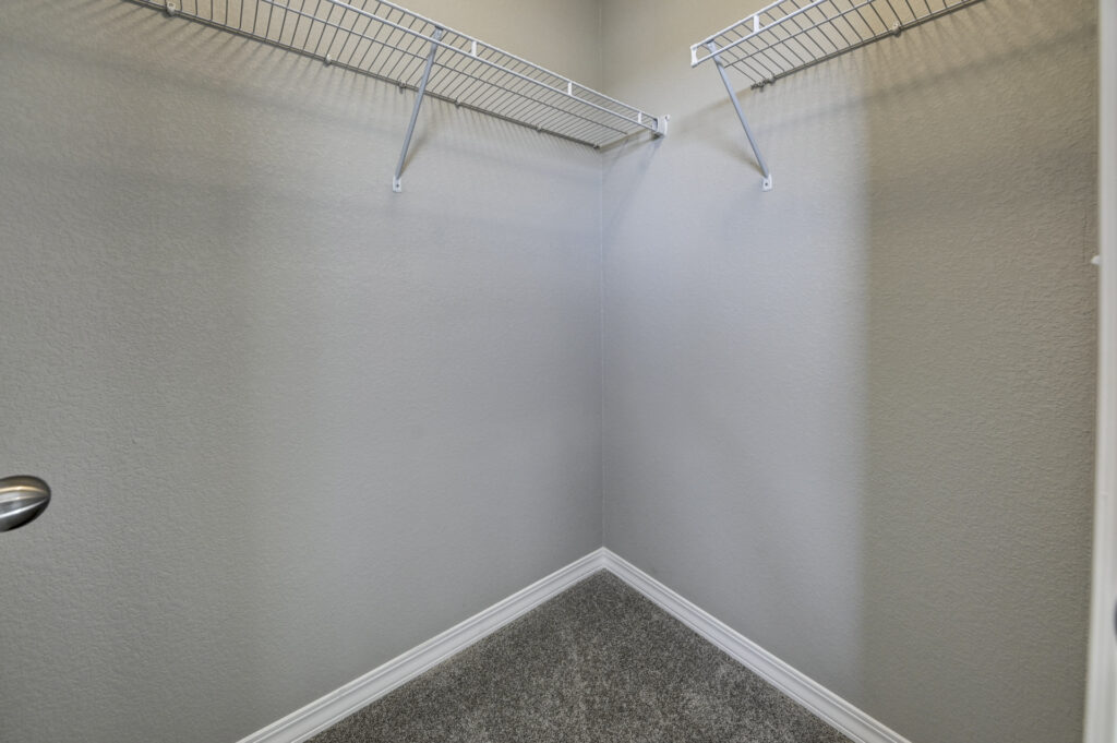 Small walk-in closet with carpeted floor and white wire shelving on two walls.