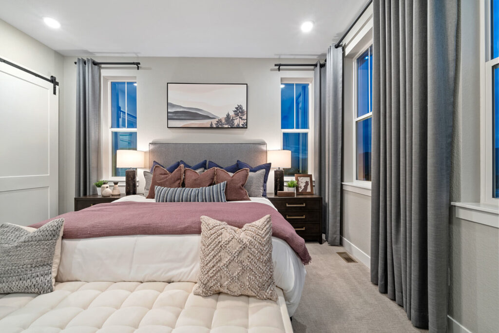 Straight-on view of a made bed with artwork above and matching nightstands and lamps.