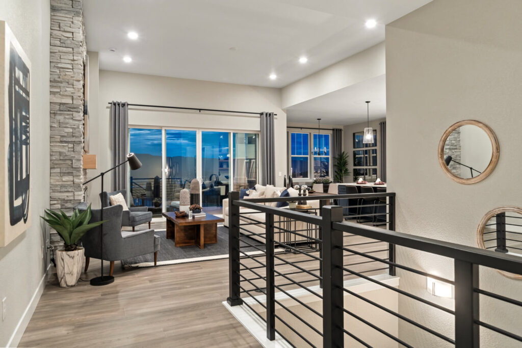 Interior upper-level landing looking into an open living area with sliding glass doors and modern rail.