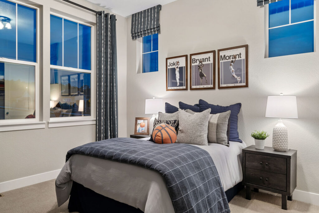 Staged bedroom with navy plaid bedding, basketball on bed, framed sports prints above headboard.