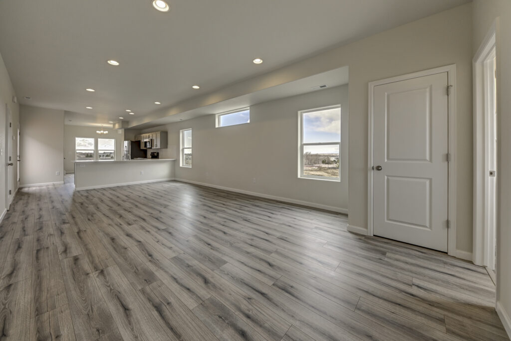 Open-plan living area with light gray wood-look flooring and recessed ceiling lights.