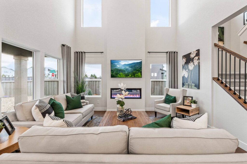 Symmetrical two-story living room with high windows, sofas, and a TV above a fireplace.