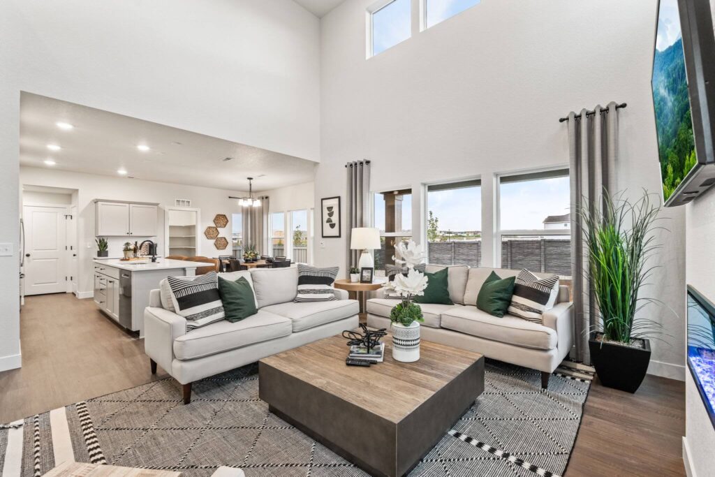 Bright living room with two beige sofas, large square wood coffee table, and tall windows.