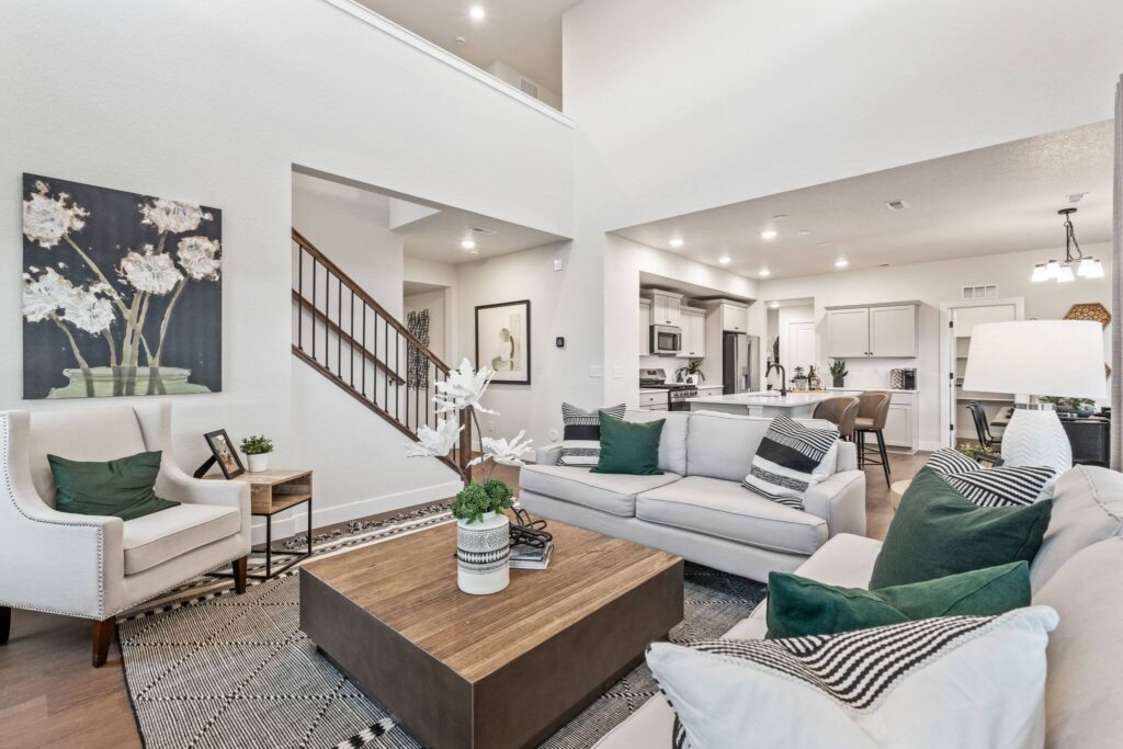 Sitting area view showing sofas, armchair, staircase, and open-plan kitchen beyond.