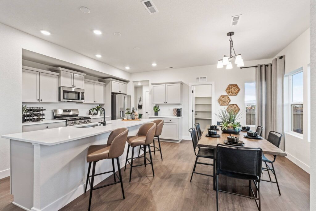 Kitchen and dining area with long island, three bar stools, and a rectangular dining table.