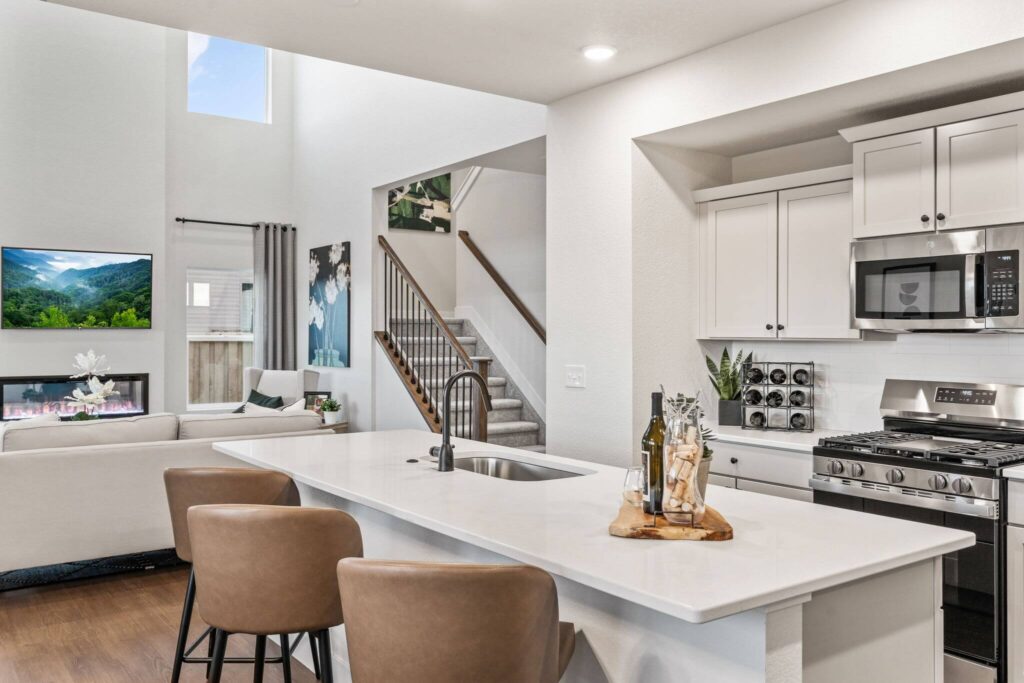 Kitchen island and seating with a staircase and living room visible in the background.