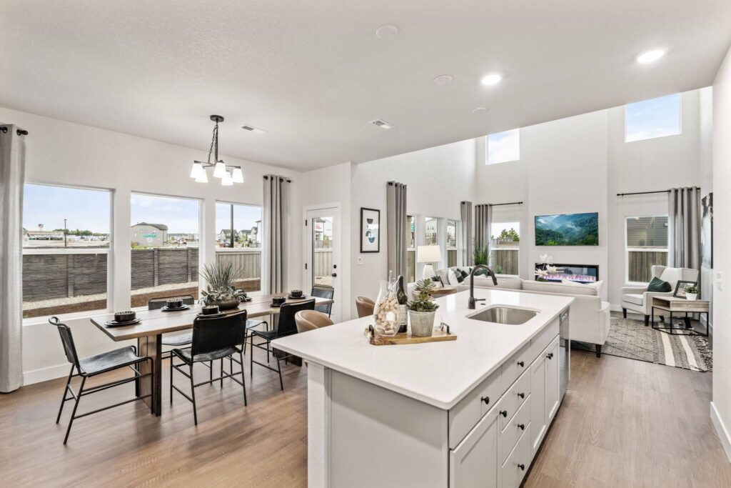 Kitchen island view toward dining area and living room with large windows and plentiful light.