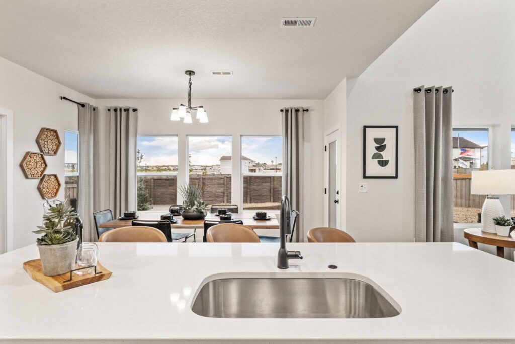 Sink and island foreground with dining table and large patio windows beyond.
