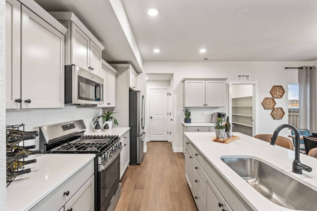 Bright modern kitchen with center island, stainless appliances, white cabinetry, and wood-look flooring.