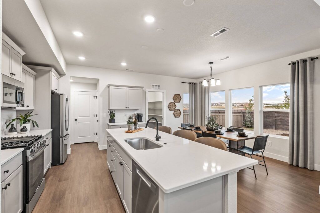 Open-concept kitchen and dining area with a long island, pantry door, and large windows.