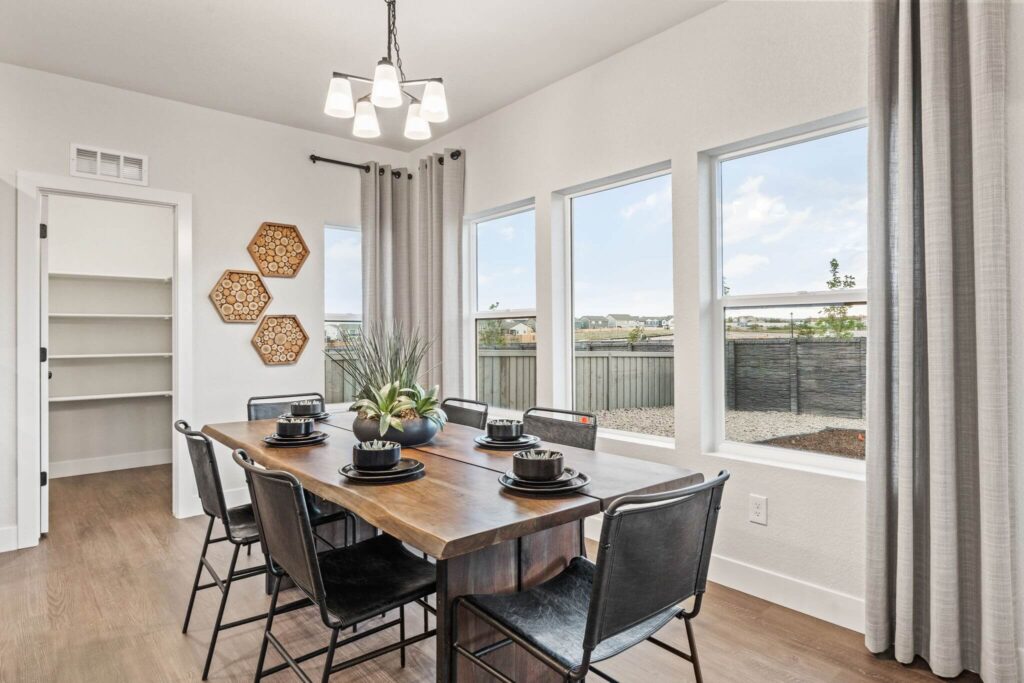 Dining area with a wooden table set for six, large windows, light fixture, and curtains.