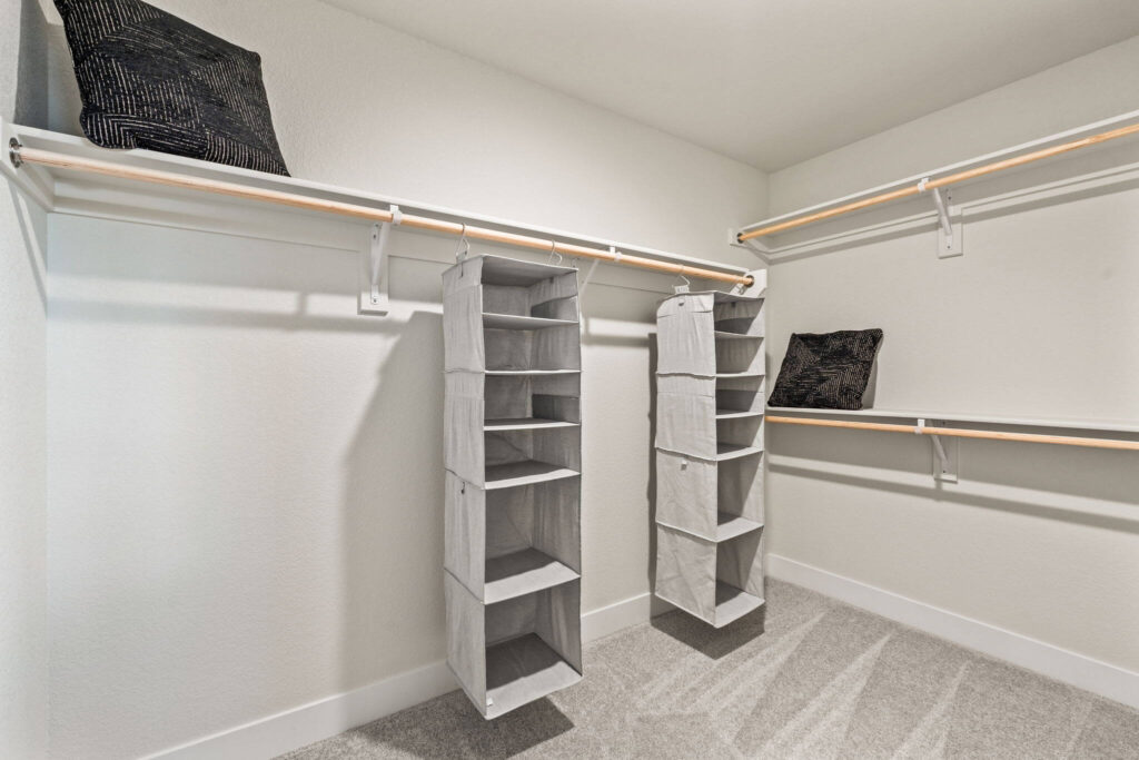 Walk-in closet with hanging rods, shelving, and two hanging fabric storage organizers.