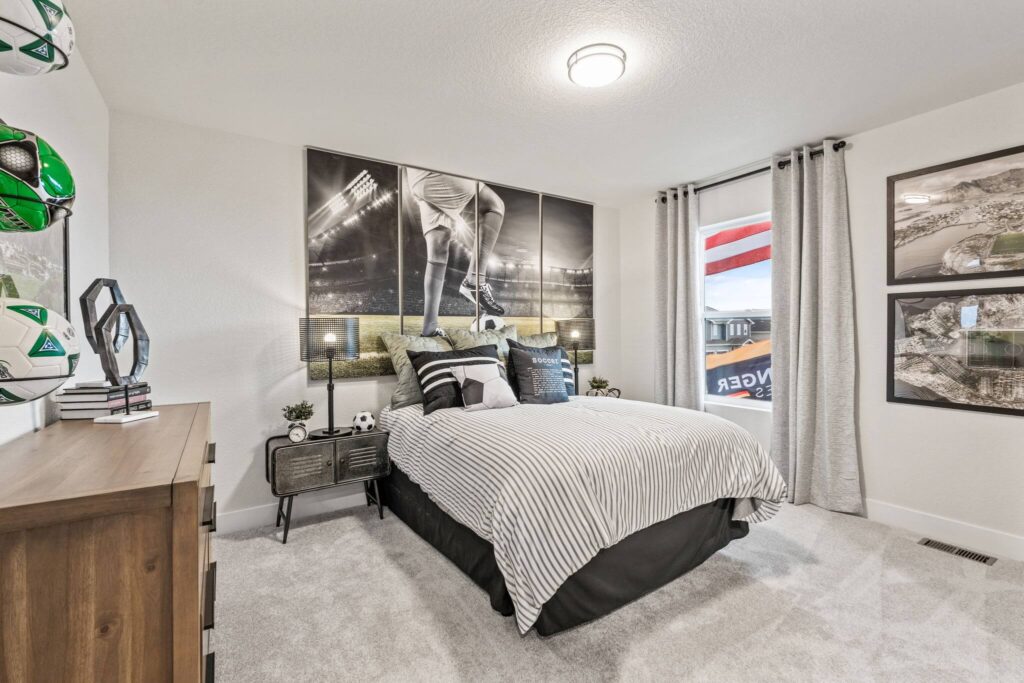 Staged bedroom with a bed, soccer-themed wall art and dresser under ceiling light.