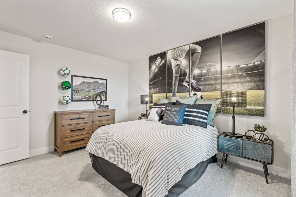 Furnished bedroom with bed, bedside tables, dresser and large sports mural above the bed.