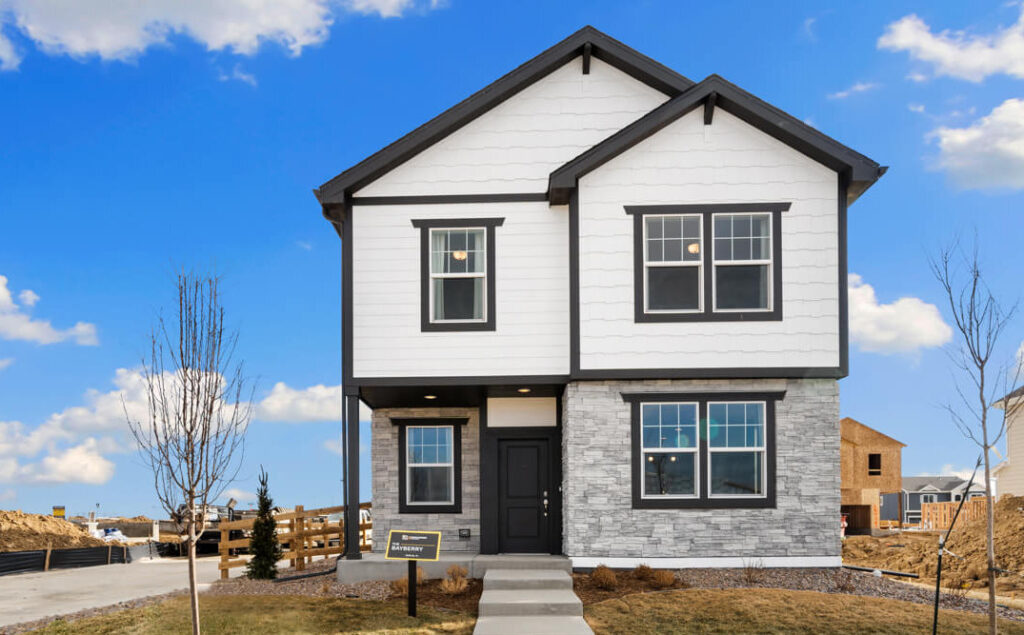 Two-story finished home exterior with white siding, dark trim, stone veneer base, and front walkway.