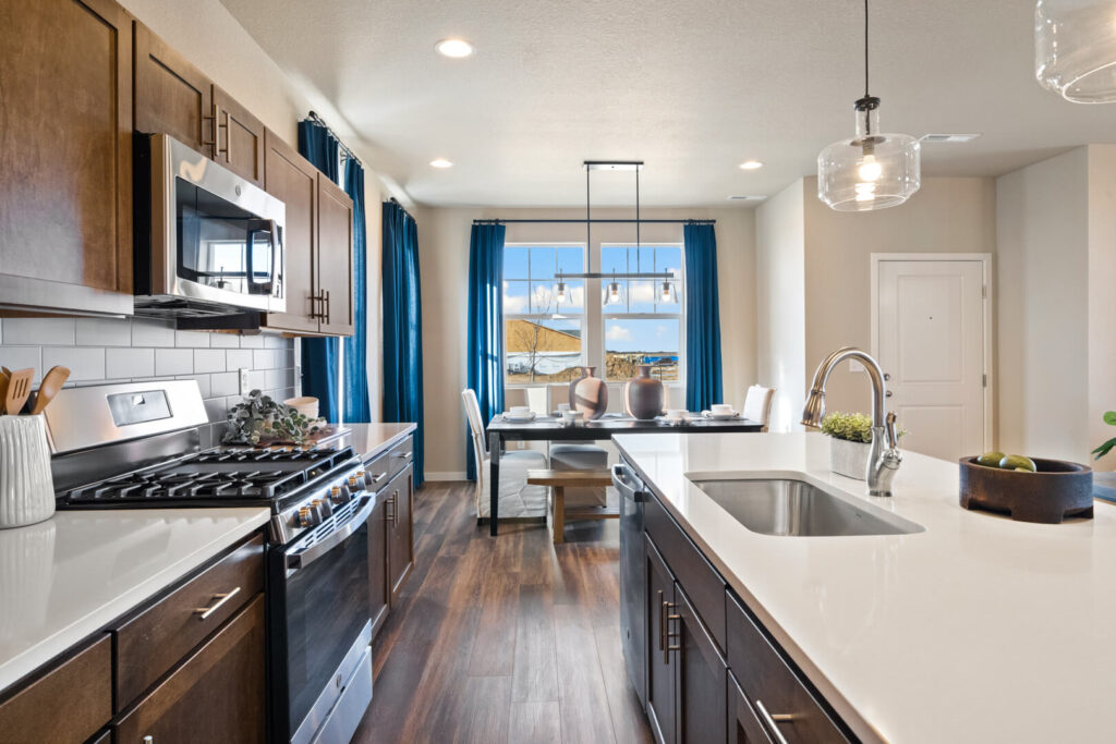 Kitchen island and stovetop with dining nook and large window framed by blue curtains.