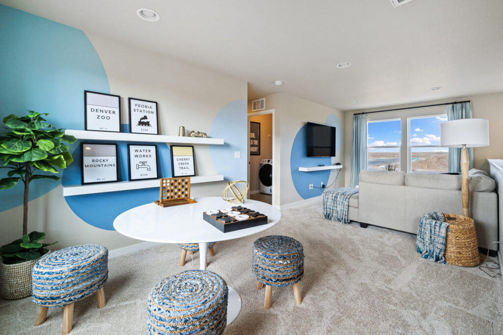 Bright loft game area with round table, woven stools, shelving and blue circle wall accents.